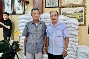 居士林林长江忠盛（左）把大米转交给第二坊祖国阵线委员会副主席黎文雄。