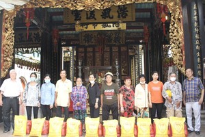 义安会馆理事长陈裕（左一）向贫困乡亲派发盂兰赈济品。