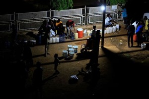 五月份喀土穆停电期间，人们聚集在一起利用发电机的光线取水。（图：路透社）