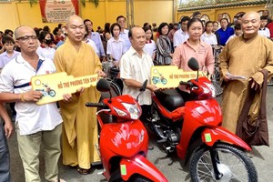 第八郡郡委副书记杜友智（左三）、龙华寺住持释慧功（左二）和常光寺院主释真静（右一）向贫民赠送摩托车。