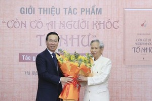 国家主席武文赏（左）向作家武伯强赠送鲜花表示祝贺。（图：越通社）