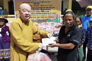 第十一郡莲华寺住持释惟镇法师向少数民族同胞赠送礼物。