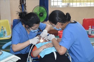 牙科医师在为一名残疾孤儿诊治牙科病。（图：越通社）