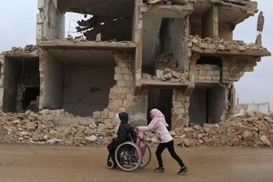 在叙利亚西北部的伊德利卜，放学后，一名女孩帮助妹妹一起回家。（图：联合国）