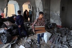 11月22日，在加沙地带南部城市汗尤尼斯，巴勒斯坦人查看遭以色列袭击后的建筑废墟。（图：新华社）