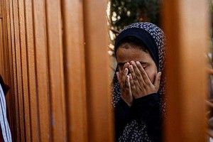 以哈冲突造成大量人员伤亡。图为12月9日，一名巴勒斯坦女童出席一场葬礼时忍不住掩面痛哭。（图：路透社） 