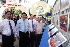 嘉宾们参观“芹苴市-建设与发展20周年”图片展。（图：维魁）