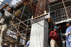 卡塔尔一处建筑工地上，移民工人在搬运钢筋。（图：联合国）