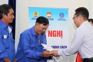 市越南祖国阵线委员会副主席范明（右）向贫困者颁赠社保册。（图：红海）