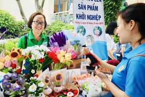 钩针编织、经济发展相助俱乐部主任石玉霞（左边）值越南企业家日，参加第八郡各经营户、企业的劳务、产品推广、介绍、展览会。