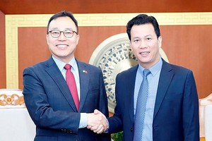 韩国驻越南特命全权大使崔英三（左）同资源与环境部长邓国庆达成合作。