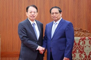 政府总理范明政（右）与亚洲开发银行行长浅川雅嗣握手合影。（图：越通社）