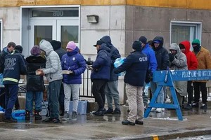 1月12日，芝加哥冬季暴风雨期间，一群移民在移民登陆区外领取食物。（图：路透社）