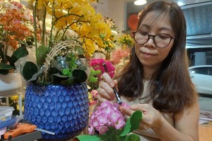 梁氏恒仔细地给粘土绣球花上色。