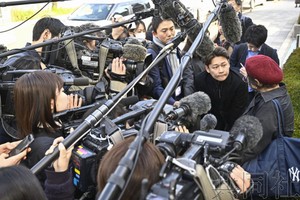 小林制药公司股东大会召开之前，股东（右一）接受采访。（图：共同社）