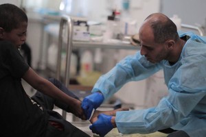 联合国近东救济工程处工作人员在加沙为男孩提供医疗服务。（图：联合国）