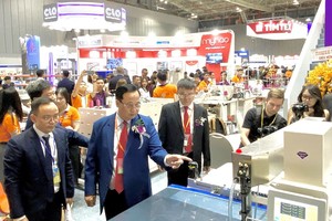 越南纺织协会主席武德江（左二）参观展摊。