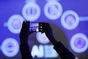 2024年2月27日，在西班牙巴塞罗那举行的2024年世界移动通信大会上，与会者在“算力网络：智能网络赋能智慧世界”专题论坛上拍摄关于AI内容的幻灯片。（图：新华社）