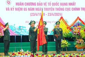 边防部队政委阮英俊中将为边防部队传统旗帜上佩挂一等捍卫祖国勋章。（图：阮明）