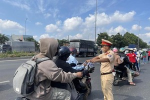 交警站在1号国道路旁向回乡度假的劳动者和学生赠送矿泉水。（图：秋红）