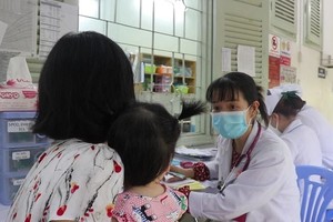 医生为手足口病患童进行检查及问诊。