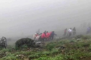 五月二十日，救援人员在飞机失事现场转移遇难者遗体。（图：AFP）