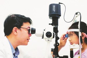 陈廷明辉博士、医生为一名病童检查视力。