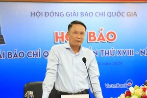 越南新闻工作者协会常务副主席阮德利在新闻发佈会上公布获奖的报刊作品。（图：何阮）