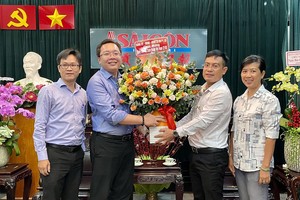 第五郡第一坊人委会主席武明哲向本编委文忠孝（右二）赠送鲜花祝贺。