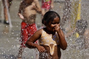 2024年6月22日，一名儿童在美国加利福尼亚州奥兰治县的一处喷泉戏水降温。（图：新华社）