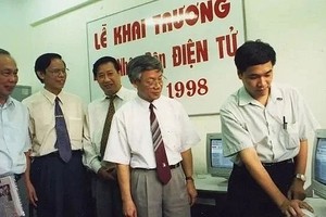 在1998年6月21日，时任党中央政治局委员、负责思想-文化与教科工作的阮富仲同志（右二）在《人民报》电子版开刊当天检查新闻报导资料。