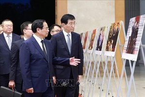 政府总理范明政（前左）向中国政协主席王沪宁介绍越南共产党中央总书记阮富仲的对外活动。（图：越通社）