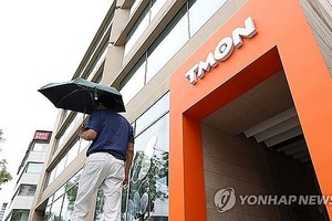 7月24日，一名男性撑伞走过位于首尔江南区的TMON总部大楼。（图：韩联社）