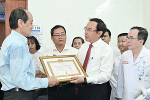 黎光成同志家人代为接受市委书记阮文年颁授的80年党龄纪念章《决定》。（图：越勇）