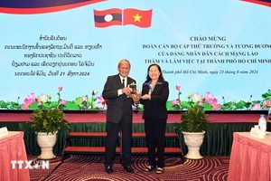 市人民议会主席阮氏丽（右）向老挝占巴塞省委副书记赛通·沙亚冯赠送礼物。（图：越通社）