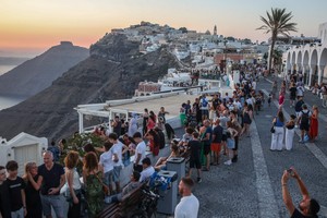 7月19日，大量游客在希腊圣托里尼岛拍摄日落美景。（图：AFP）