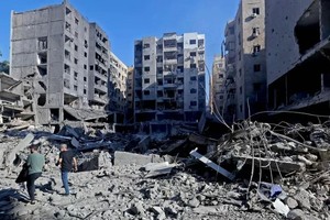 在黎巴嫩首都贝鲁特南郊，人们走在建筑废墟中。（图：新华社）