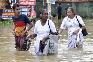 10月12日，在斯里兰卡加姆珀哈，人们经过被淹没的街道。（图：新华社）