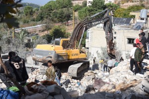 在黎巴嫩阿卡尔，当地居民清理以军空袭留下的废墟。（图：新华社）