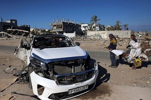 2024年11月30日，人们在加沙地带南部的汗尤尼斯检查一辆遭以色列袭击的汽车，据报道，袭击造成 5 人死亡。（图：AFP）