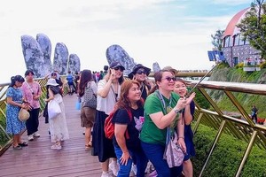 国际游客兴奋地在岘港市巴拿山太阳世界旅游区的金桥上打卡。（图：陈黎霖）