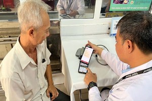 医务人员亲自为一位大叔指导安装VNeID和使用电子健康手册。（图：市党部新闻网）