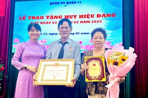 荣获55 年党龄纪念章的何永忠（中）与妻子阮氏秋（右一）合影。