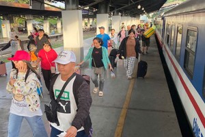 处境艰困的工人正在沿路轨徒步上月台准备上列车回乡过年。（图：黄雪）