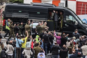 2月22日，在佩塔提克瓦一处医疗中心的门口，获释的以色列被扣押人员向人群致意。（图：新华社）