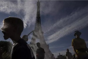 图为2024 年法国巴黎夏季奥运会期间，人们在埃菲尔铁塔外的薄雾下乘凉。（图：AP）