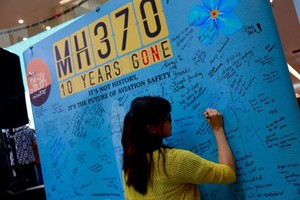 在MH370 10周年纪念日上，一名女性乘客亲属在留言板上留言。（图：路透社）