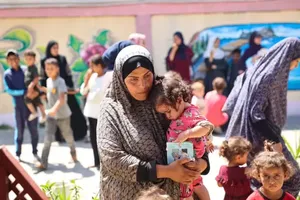  在加沙地带由联合国儿童基金会支持的一家诊所，一名妇女抱着她的女儿等待接受营养筛查。（图：UNICEF）