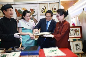 越南政府总理范明政与泰国总理佩通坦参观了解越南东胡画制作工艺。（图：越通社）