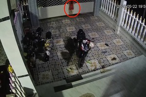 女童在卷帘门上升时攀爬（红圈示）。（图：视频截图）